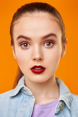 Sarı arka planda poz veren kot ceketli güzel duygusal bir kızın portresi. Güzellik, moda. Gençlik tarzı. 