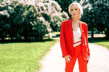 Yaşlı, şık bir kadının yaz parkındaki portresi. Güzellik, moda.