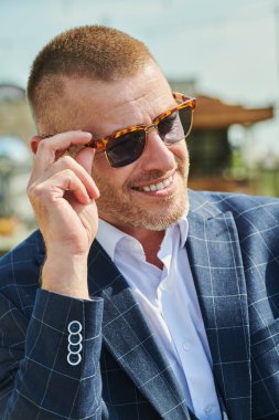 Zarif takım elbiseli ve gözlüklü, gülümseyen, başarılı, olgun bir adamın yakın plan portresi. Yaz dönemi. Erkek tarzı. Erkekler için optik.