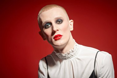 Kadın makyajlı solgun bir gencin portresi ve siyah bir arka planda kırmızı mücevherli taç..