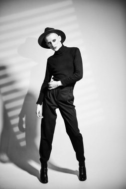 Kadın makyajlı solgun bir gencin portresi ve siyah bir arka planda kırmızı mücevherli taç..