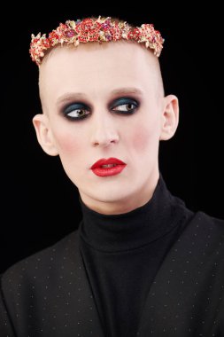 Kadın makyajlı solgun bir gencin portresi ve siyah bir arka planda kırmızı mücevherli taç..