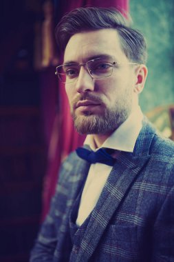 Zarif takım elbiseli yakışıklı zengin adam lüks dairelerde duruyor. İş adamı portresi. Erkek modası..