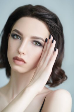 Güzellik konsepti. Güzel esmer bir kızın portresi. Gece makyajı ve saç stili ile beyaz arka planda stüdyoda poz veriyor.. 