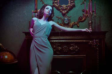 Güzel esmer, gece makyajı ve lüks bir dairede şık bir elbise içinde poz veren güzel bir kız. Moda fotoğrafı.. 