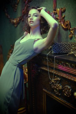 Güzel esmer, gece makyajı ve lüks bir dairede şık bir elbise içinde poz veren güzel bir kız. Moda fotoğrafı.. 