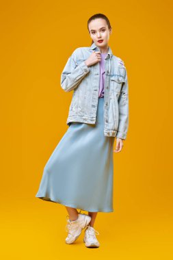 Stüdyoda sarı arka planda hareket halinde duran kot pantolonlu manken. Moda, yeni yaz tarzı..