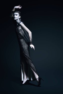 Siyah arka plan üzerinde kabak kafatası makyajı olan zarif bir kadının tam boy portresi. Cadılar Bayramı. Ölülerin Günü.