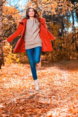 Sonbahar ormanında atlayan güzel bir genç kadının uzun bir portresi. Yaşam tarzı, sonbahar modası, güzellik. 