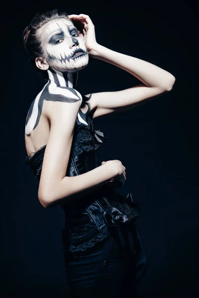 Beautiful graceful woman with pumpkin skull makeup over black background. Halloween. Day of The Dead.