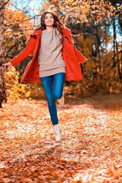 Sonbahar ormanında atlayan güzel bir genç kadının uzun bir portresi. Yaşam tarzı, sonbahar modası, güzellik. 