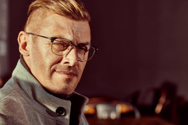 Yakışıklı, orta yaşlı, şık giyinmiş ve gözlüklü bir adamın sokakta duran portresi. Erkek güzelliği, moda. Optik biçimi.