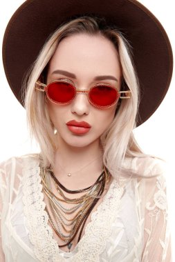 Yaz stili. Açık beyaz dantelli elbise ve güneş gözlüğü takan sarışın güzel bir kızın portresi. Beyaz arkaplanda stüdyo portresi.