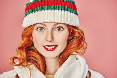 Örgü şapka ve atkıyla farklı pozitif duyguları olan güzel kızıl saçlı kız. Pembe arka planda stüdyo portresi. Örgü tarzı..