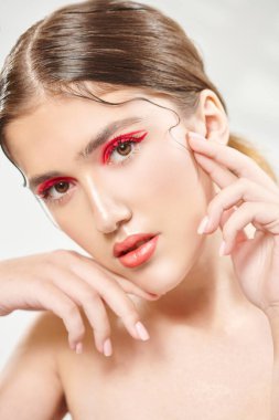 Makyaj ve kozmetik konsepti. Parlak makyajlı ve gözlerinde kırmızı oklar olan güzel bir kızın portresi. Güzellik, moda.