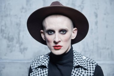 Kadın makyajlı solgun bir gencin portresi ve siyah arka planda kırmızı mücevherli taç. Avangard modası. 