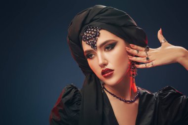 Arap güzelliği, moda. Geleneksel makyajlı, siyah tesettürlü ve siyah arkaplanlı güzel bir doğulu kadının portresi. Makyaj ve kozmetik. 