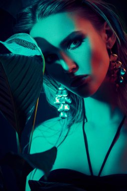 Palmiye yapraklarının arasında ıslak saçlı güzel bir tropikal kadının portresi. Güzellik, moda ve kozmetik konsepti. Tropikal ülkelerde tatil.