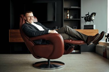 Zarif takım elbiseli, gözlüklü, deri koltukta oturan saygıdeğer orta yaşlı bir işadamının portresi önemli bir soru üzerine kafa yoruyor. Başarı ve liderlik.