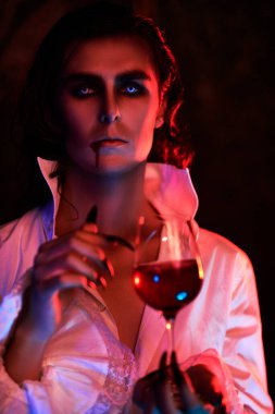 Mum ışığında bir bardak kanı olan yakışıklı, kana susamış bir vampirin portresi. Cadılar Bayramı.