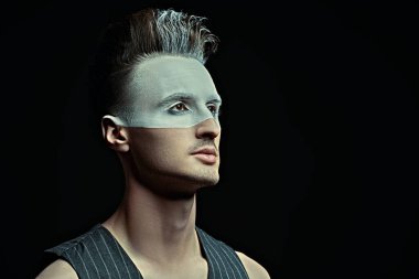 Siyah arka planda beyaz boyalı yakışıklı bir gencin sanat portresi. Erkek güzeli, moda. Saç stili ve kozmetik.