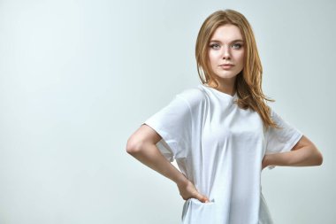 Kameraya gülümseyen sarı saçlı ve doğal makyajlı güzel bir genç kadının portresi. Beyaz bir arka planda stüdyo çekimi. Güzellik endüstrisi. Mutlu yaşam konsepti.