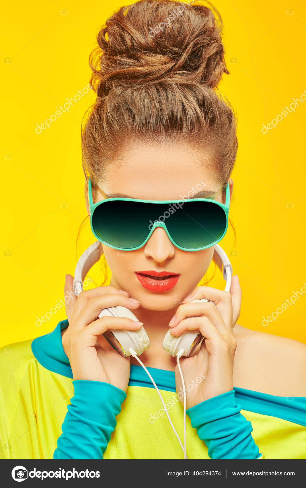 穿着五彩缤纷的衣服和太阳镜的酷现代女孩在耳机里听音乐黄色背景上的工作室肖像明亮的生活方式 图库照片 C Prometeus