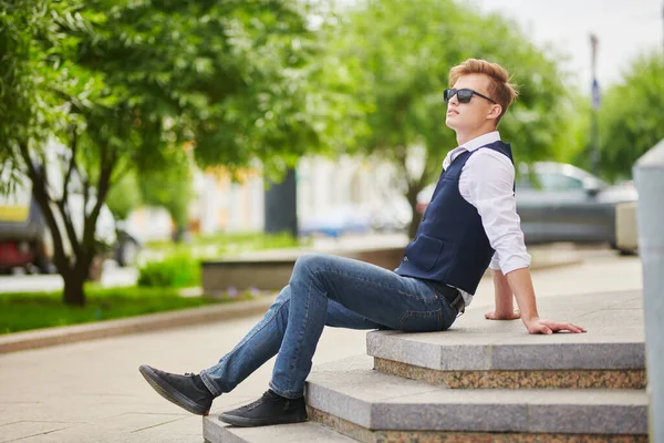 Yakışıklı genç adam şehirde geziniyor ve gülümsüyor. Yaz modası. Yaz tatili ve tatil.