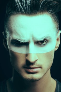 Sanat konsepti. Acımasız, ciddi bir adamın portresi somurtkan, yüzünde beyaz boya ve siyah arka planda saçlar. Erkek güzelliği, moda. Saç stili ve kozmetik.