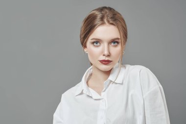 Sarışın ve doğal makyajlı güzel bir genç kadının portresi. Stüdyo görüntüsü gri arka planda. Güzellik endüstrisi.