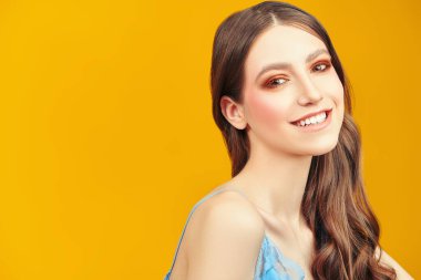 Makyaj ve makyaj malzemeleri. Sarı arka planda kahverengi makyajlı güzel bir kızın portresi..