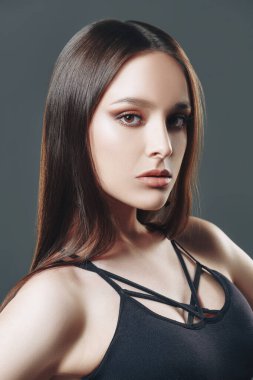 Stüdyoda gri arka planda siyah kapaklı poz veren çekici bir model. Güzellik, moda.