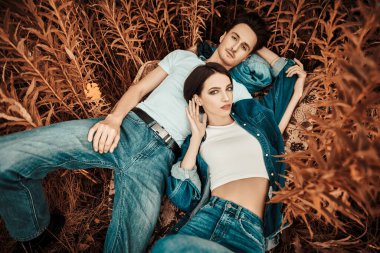 Birbirine aşık genç bir çiftin portresi sonbahar çimlerinde uzanan temiz havada dinleniyor. Aşık insanlar. Sonbahar mevsimi.