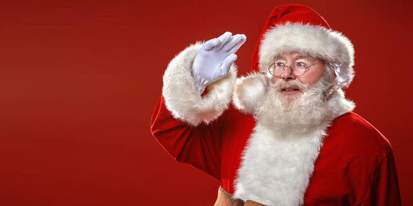 Портрет Санта-Клауса, смотрящего вдаль на красном фоне. Атмосфера праздника и магии, огни и сверкающие вокруг. С Новым годом и Рождеством! Копирование пространства.