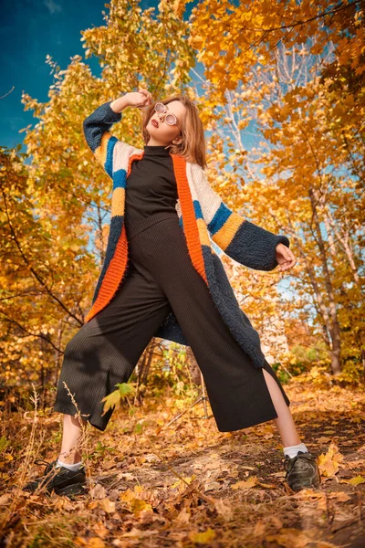 Güzel modern kız sonbahar parkında poz veriyor. Mevsimlik stil, sonbahar güzelliği, moda.