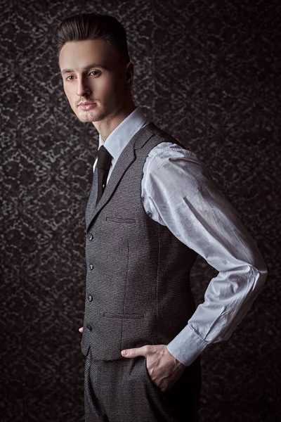 Portrait of a handsome man in elegant classic suit and a tie on a vintage background. Business style. Men's fashion.