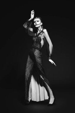 Siyah arka planda balkabağı kafatası makyajı olan zarif bir kadının tam boy monokrom portresi. Cadılar Bayramı. Ölülerin Günü.