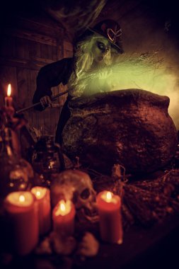 Korkunç cadı süpürgesini sihirli iksirle kazanın yanında büyülüyor. Cadılar Bayramı. Korkunç hikayeler.. 