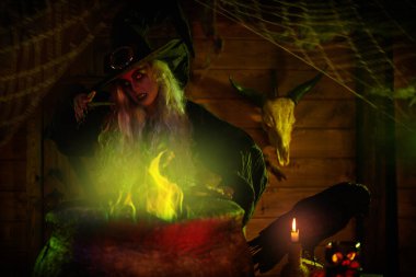 Korkunç yaşlı cadı sihirli yeşil ışıkla çevrili kazanında sihirli iksir yapıyor. Cadılar Bayramı. Korkunç hikayeler..