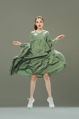 Yeni yaz stili. Uzun yeşil bir yaz elbisesi içinde açık yeşil bir arka planda hareket eden sevimli, duygusal bir kız modelin portresi. Güzellik, moda. 