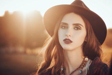 Gün batımında arka planda romantik esmer bir kızın portresi. Yaz ve sonbahar tatili. Modern gençlik yaşam tarzı.