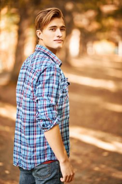 Güneşli bir sonbahar ormanında yakışıklı bir gencin portresi. Erkek güzeli.. 