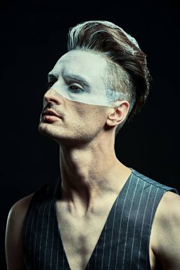Siyah arka planda beyaz boyalı yakışıklı bir gencin sanat portresi. Erkek güzeli, moda. Saç stili ve kozmetik.