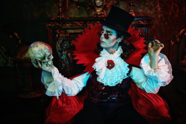 Kana susamış vampir, eski kalesinde gecenin bir yarısı kafatasıyla otururken dişlerini gösterdi. Kont Drakula. Cadılar Bayramı.