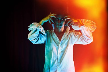 Kana susamış yakışıklı vampir, siyah arka planda, ateş ışığında duruyor. Cadılar Bayramı.