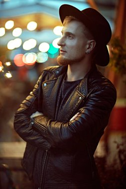 Büyük şehirde hayat. Modern genç adam büyük bir gece şehrinin caddesinde yürüyor. Hipster tarzı. 