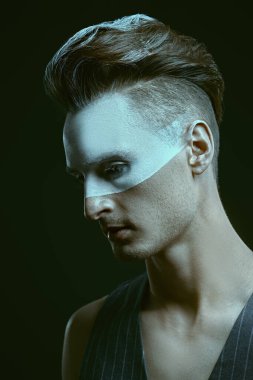 Siyah arka planda beyaz boyalı yakışıklı bir gencin sanat portresi. Erkek güzeli, moda. Saç stili ve kozmetik.