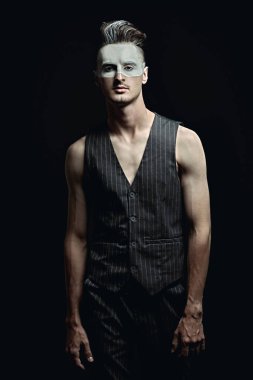 Yüzünde beyaz boya ve fotokopi alanı olan siyah bir arkaplan olan yakışıklı bir gencin sanat portresi. Erkek güzeli, moda. Saç stili ve kozmetik.