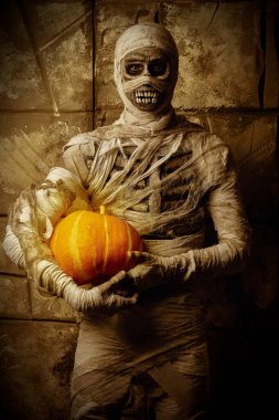 Korkunç Cadılar Bayramı mumyası eski Mısır hiyeroglifleriyle duvarın yanında duran bir balkabağı tutuyor. Cadılar Bayramı. Antik Mısır mitolojisi.