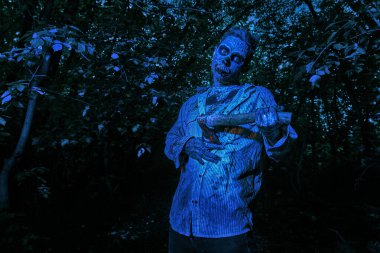 Gece ormanında elinde balta olan korkunç kanlı zombi. Cadılar Bayramı. Heyecan.